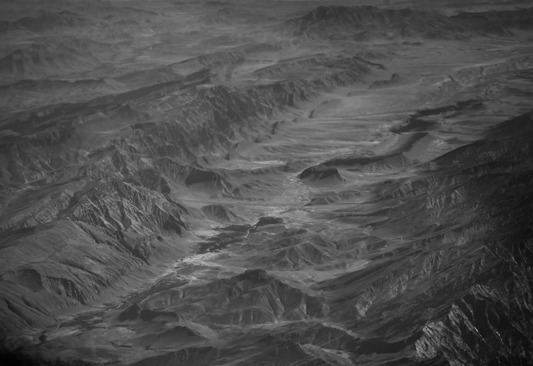 Abstrakt wirkende Gebirgs- und Wüstenlandschaft aus der Luft