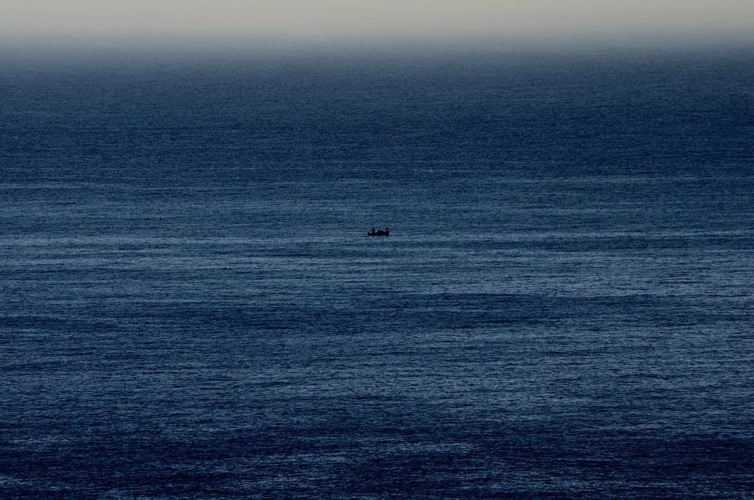 Kleines Boot allein auf einer weiten blauen Meeresfläche