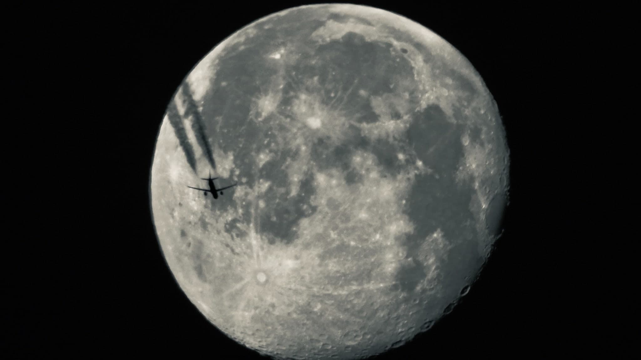 Flugzeug als Silhouette vor dem Vollmond